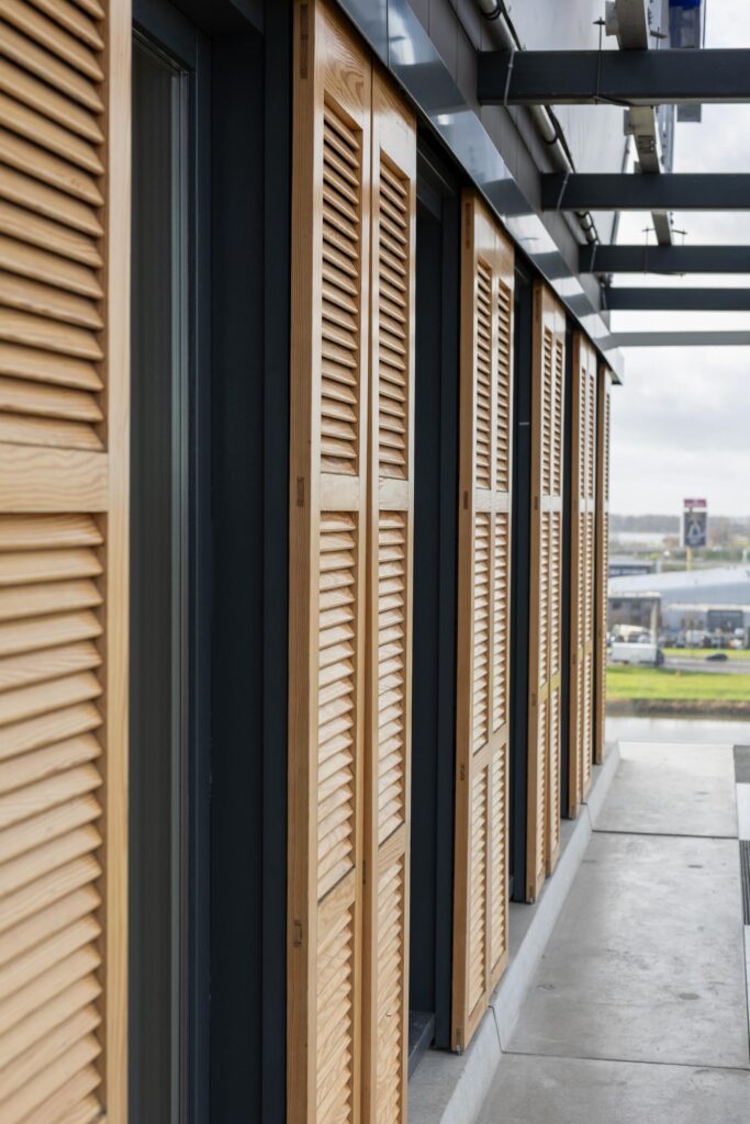 Wooden louvered shutters on the exterior of a modern building at Paasheuvelweg.