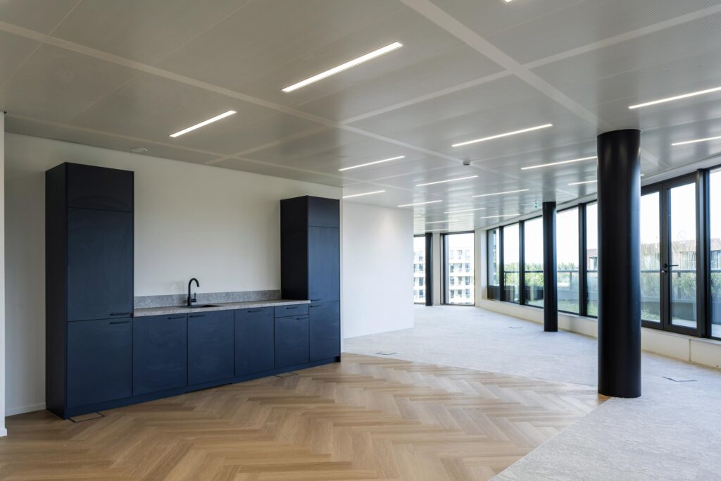 Modern office space on Gelrestraat with dark kitchen cabinets, wood-patterned flooring, and large windows providing natural light.