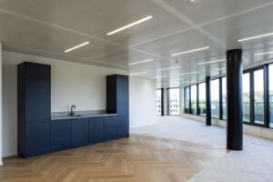 Modern office space on Gelrestraat with dark kitchen cabinets, wood-patterned flooring, and large windows providing natural light.
