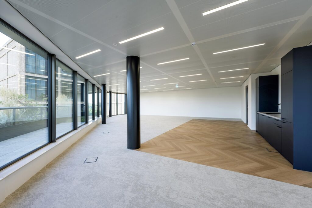 Modern, unfurnished office space on Gelrestraat with large windows, mixed flooring, and a built-in kitchenette.