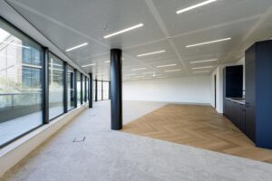 Modern, unfurnished office space on Gelrestraat with large windows, mixed flooring, and a built-in kitchenette.