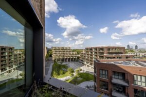 View of modern residential buildings and a central green square on Gelrestraat under a blue sky with clouds.
