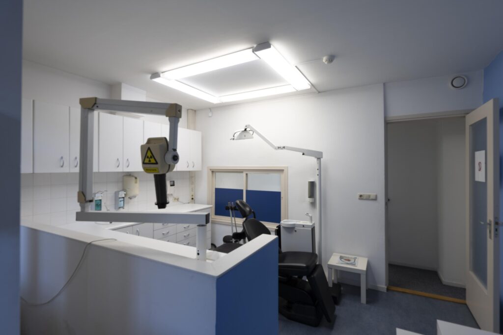 Modern dental examination room with X-ray equipment and a dentist chair.