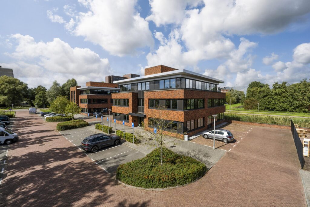 Modern office buildings on Veteranenlaan with adjacent parking spaces and greenery under a partly cloudy sky.