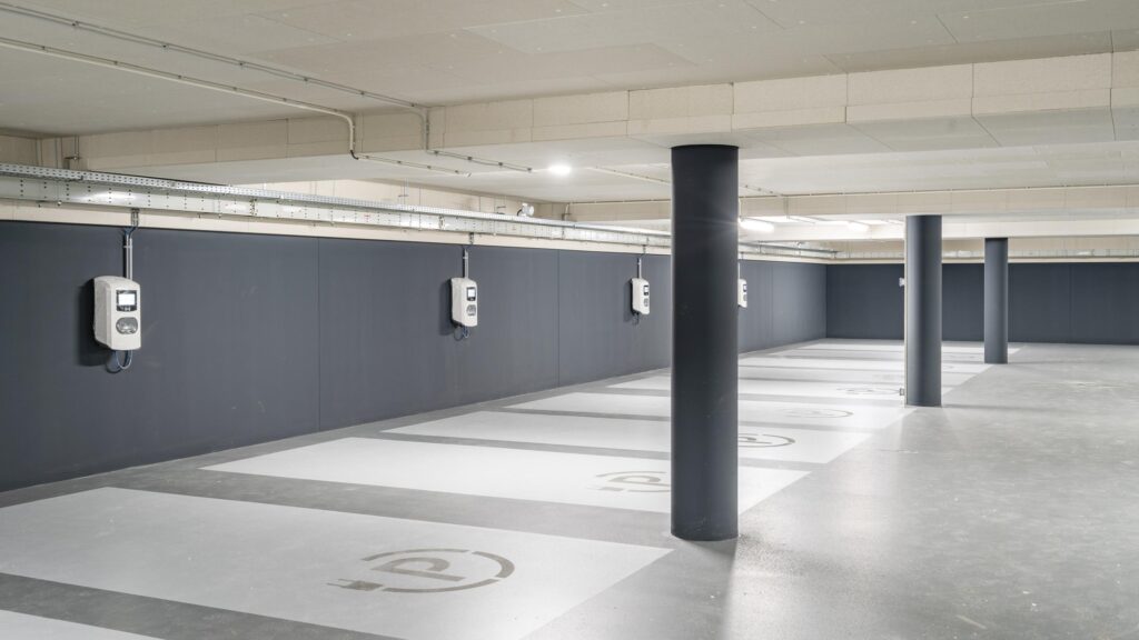 Underground parking area with multiple electric vehicle charging stations and designated charging bays.