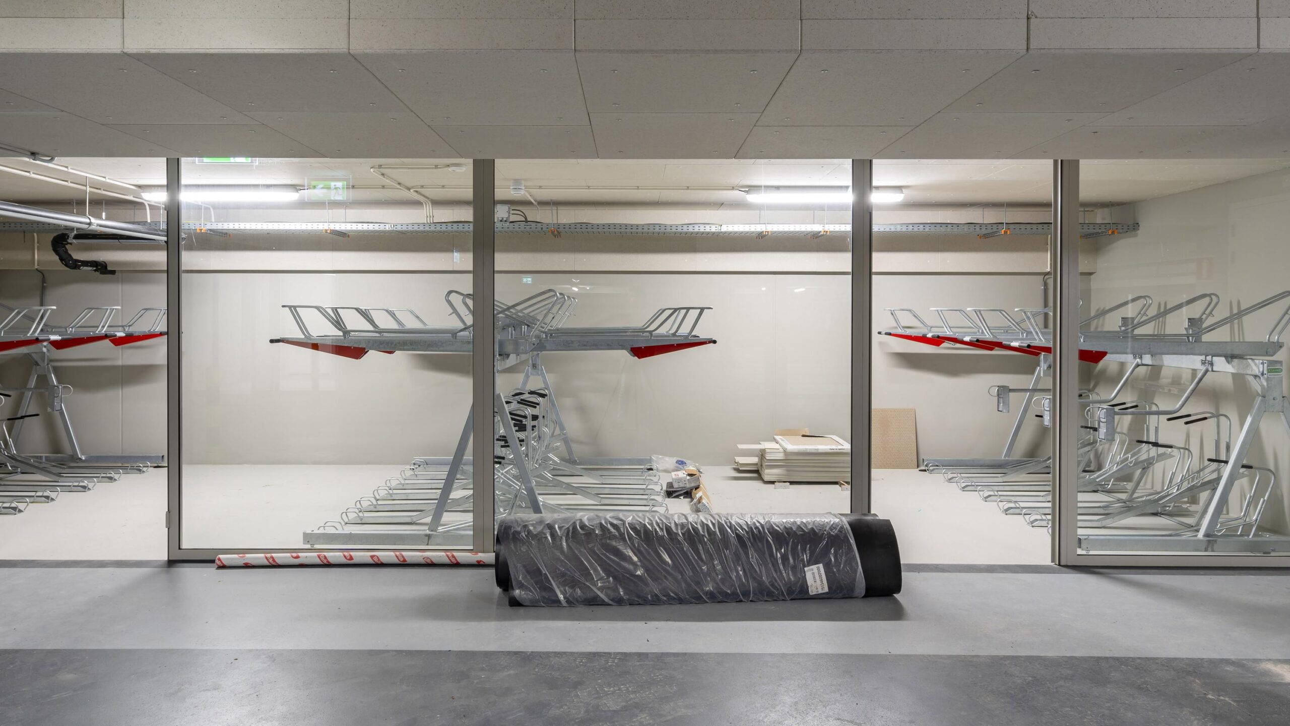 Indoor bicycle storage area with double-decker bike racks visible through glass walls.