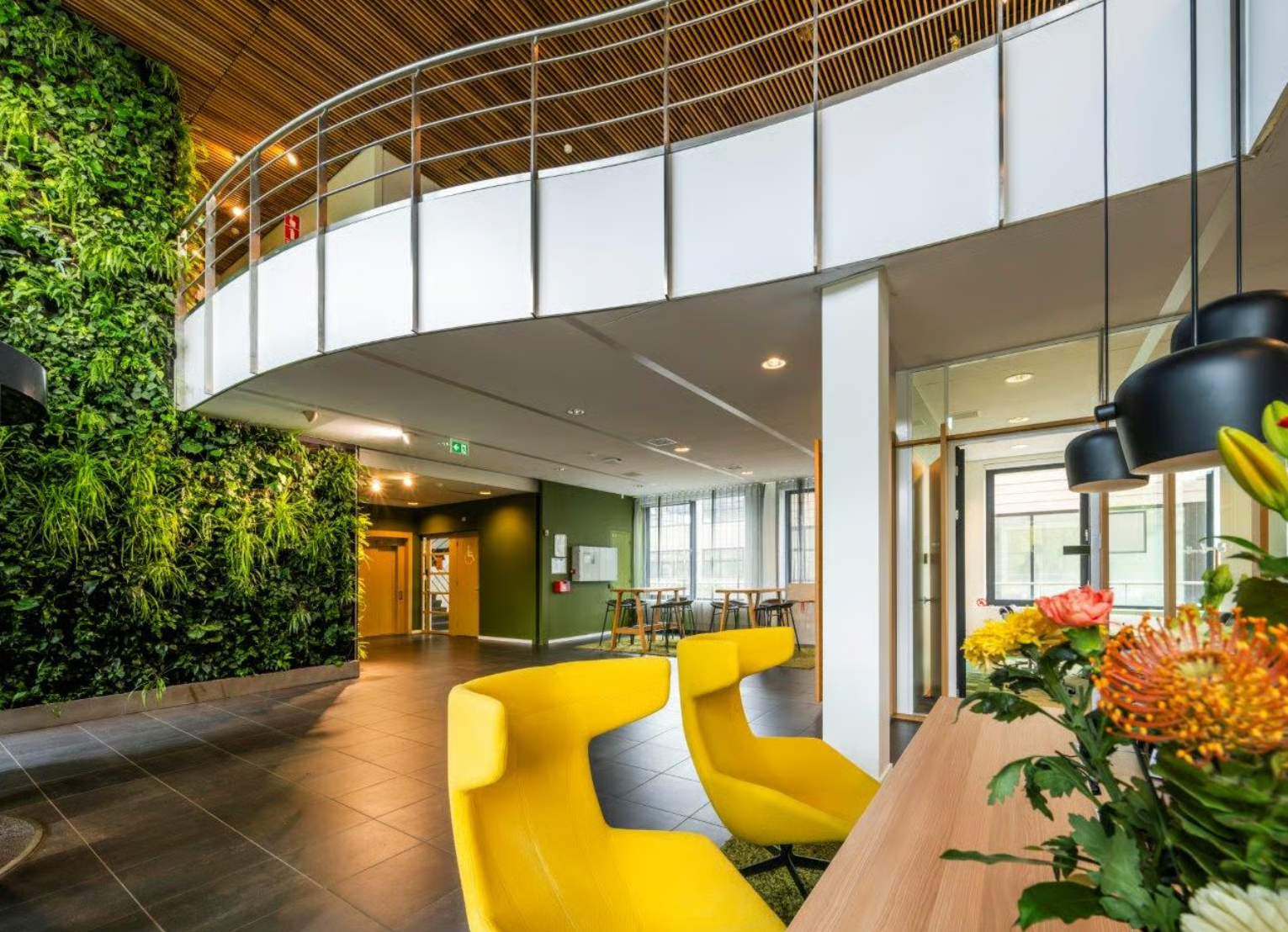 Modern office lobby on Boeing Avenue with bright yellow chairs, a green plant wall, and contemporary interior design.