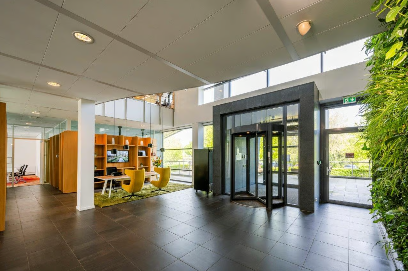 Modern office entrance at Boeing Avenue with a revolving door, green wall, and seating area.