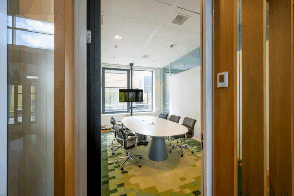 Modern meeting room on Boeing Avenue with a white oval table, six chairs, and a wall-mounted screen.