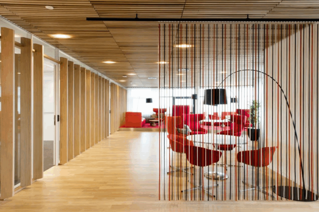 Modern office lounge area on Boeing Avenue with red and orange seating, wooden accents, and a striped room divider.