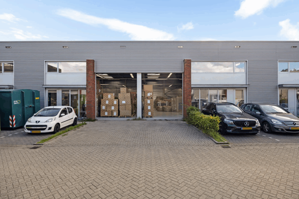 Facade of a warehouse on Schaafstraat with stacked boxes inside and parked cars in front.