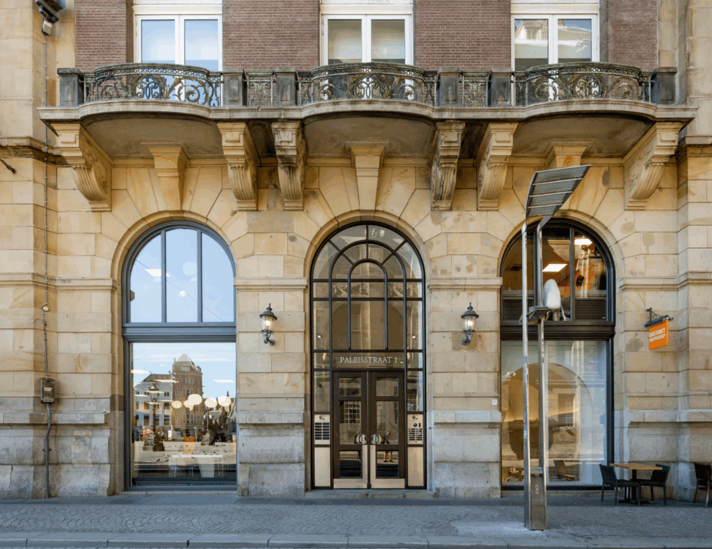 Gevel van een historisch gebouw aan de Paleisstraat 1 met boogramen, sierlijke balkons en een centrale toegangsdeur.