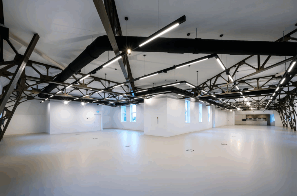 Ruim en modern interieur van Paleisstraat 1 met zichtbare stalen balken, strakke verlichting en een minimalistisch ontwerp.