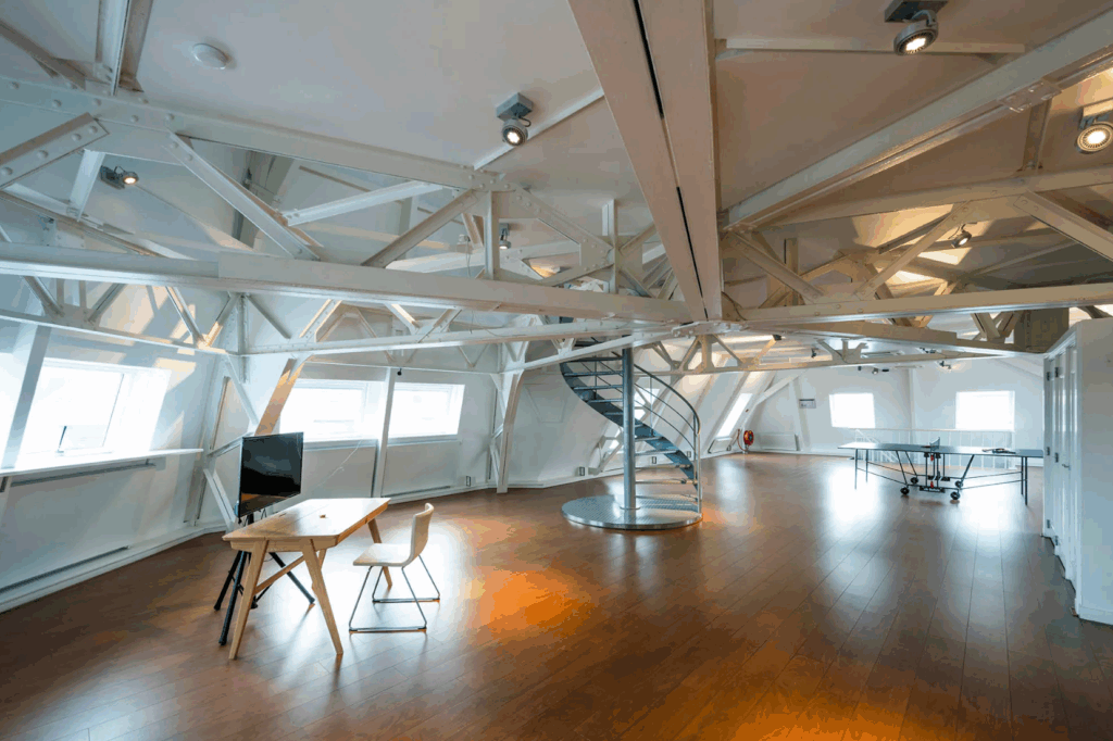 Ruim, modern zolderkantoor aan de Paleisstraat met houten vloeren, balkenplafond, een wenteltrap en een pingpongtafel.