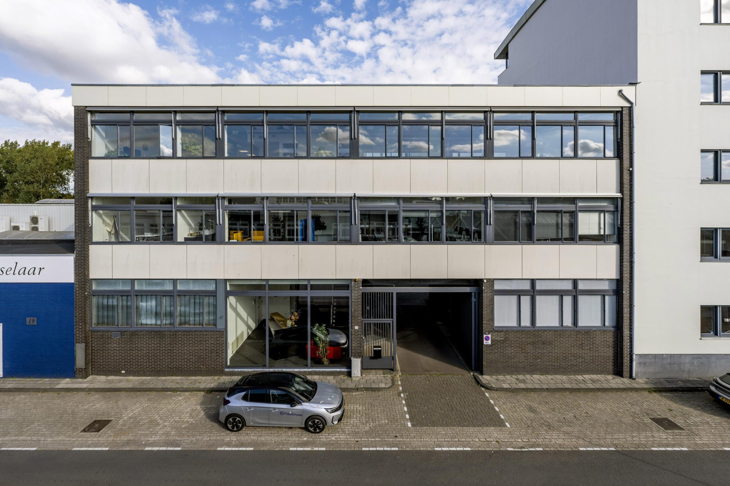 Vooraanzicht van een modern kantoorgebouw aan de Helicopterstraat met geparkeerde auto’s ervoor.
