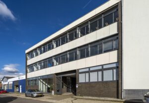 Voorgevel van een modern kantoorgebouw aan de Helicopterstraat met geparkeerde auto's ervoor.
