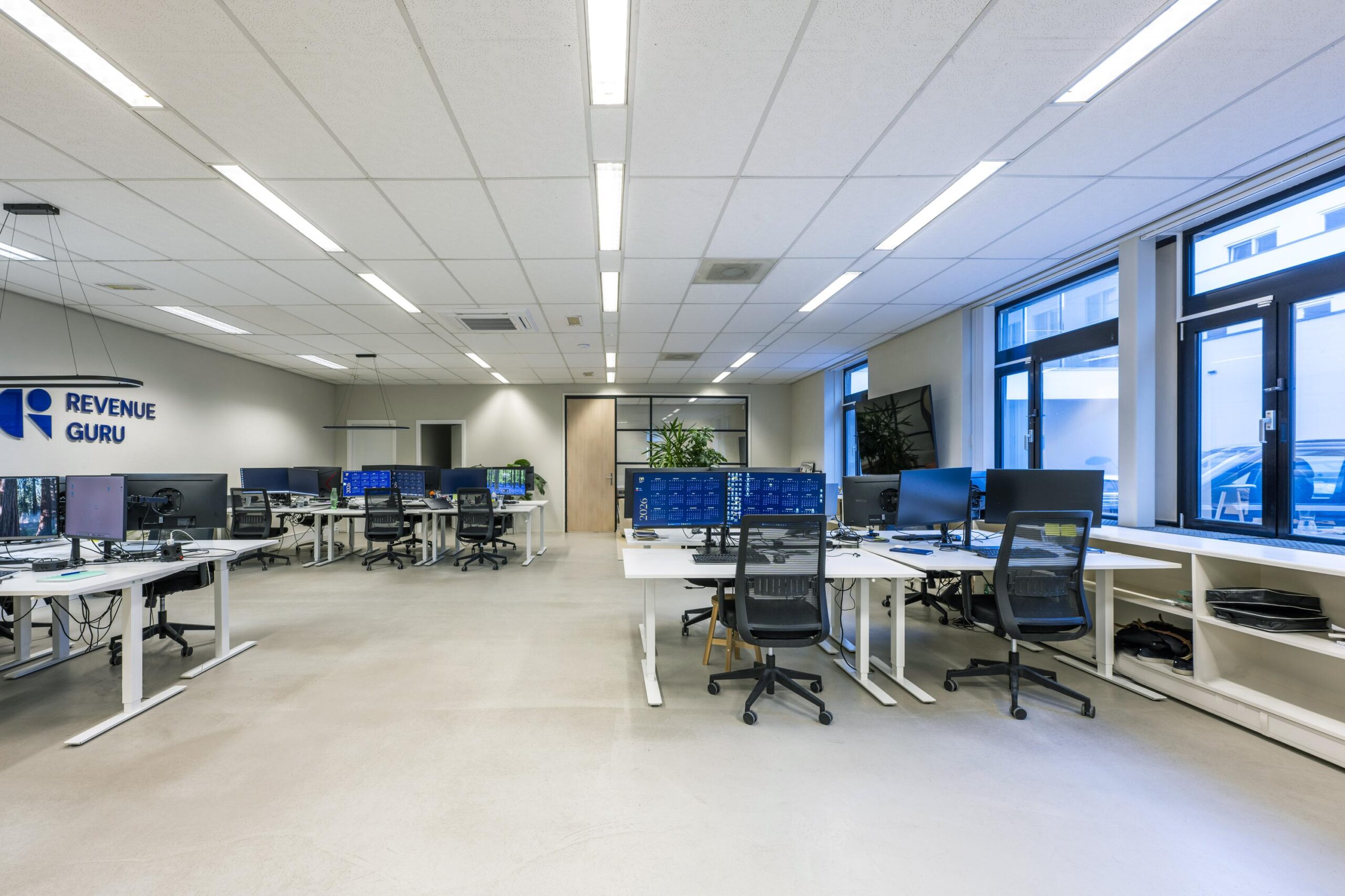 Modern en strak ingericht kantoor van Revenue Guru aan de Helicopterstraat met meerdere werkplekken en grote beeldschermen.