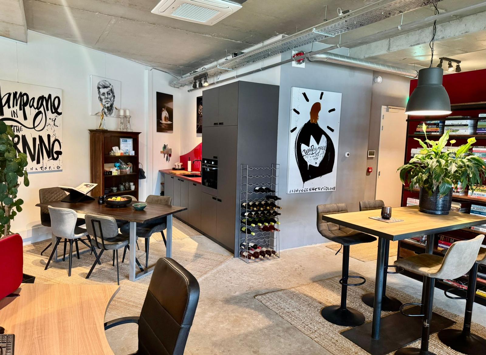 Moderne kantoorruimte met een keuken, eethoek, boekenkast en kunst aan de muur.