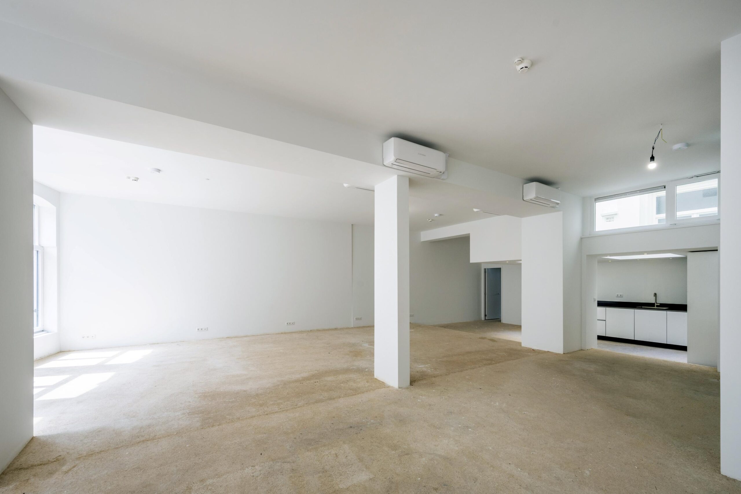 Licht, leeg interieur van een gerenoveerde ruimte aan het Damrak met open indeling en zicht op keukenblok.