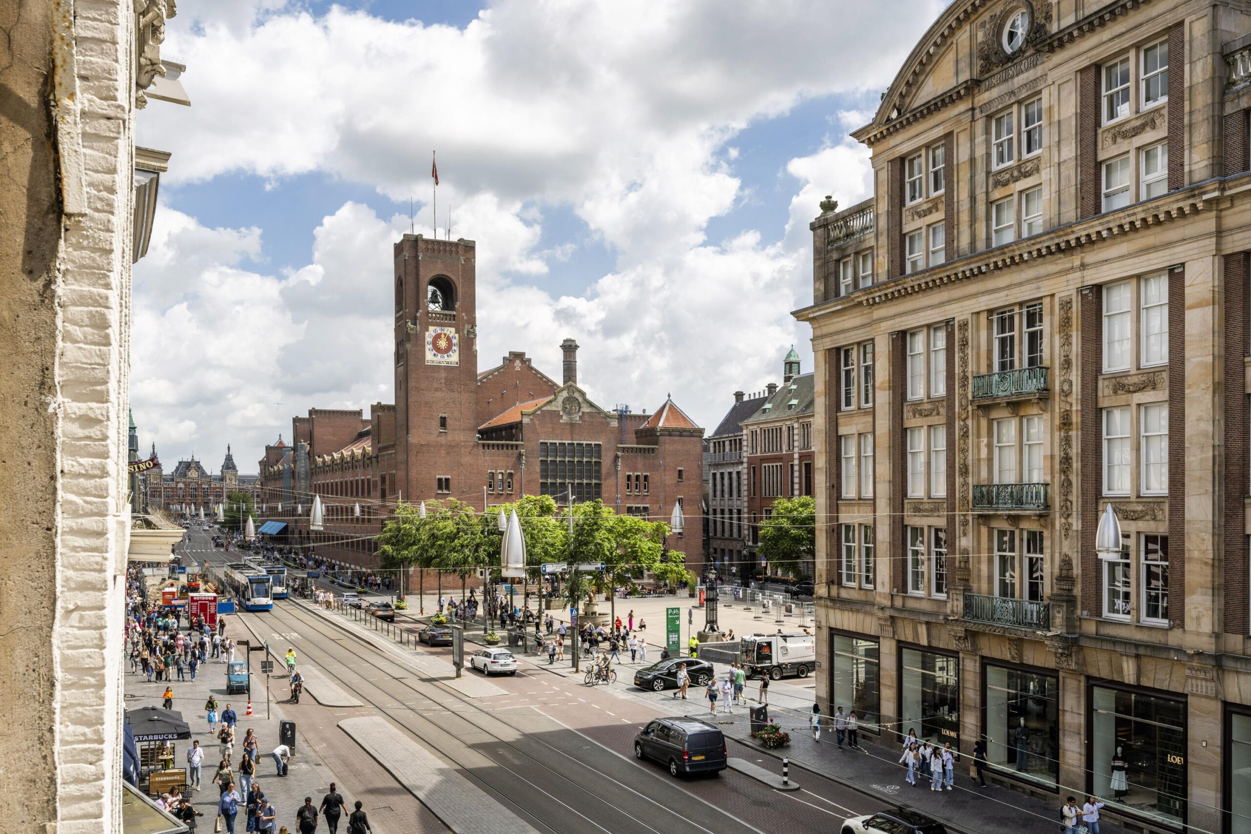 Uitzicht op de Damrak in Amsterdam met het Beurs van Berlage-gebouw en druk stadsverkeer.