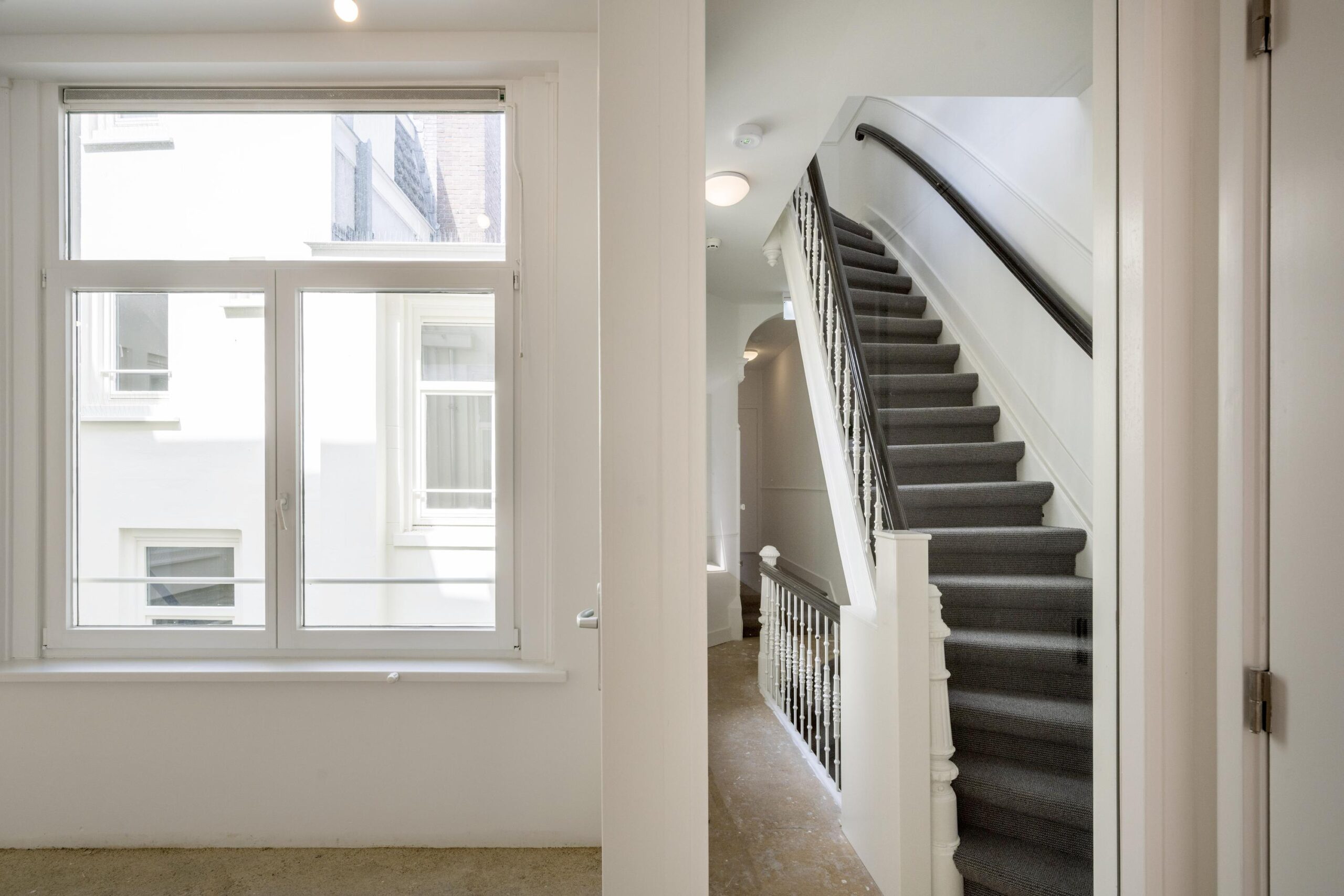 Trapopgang en raam met uitzicht op een binnentuin in een gerenoveerd pand aan het Damrak.