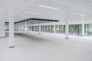Spacious, empty office floor with large windows and modern white ceiling panels.