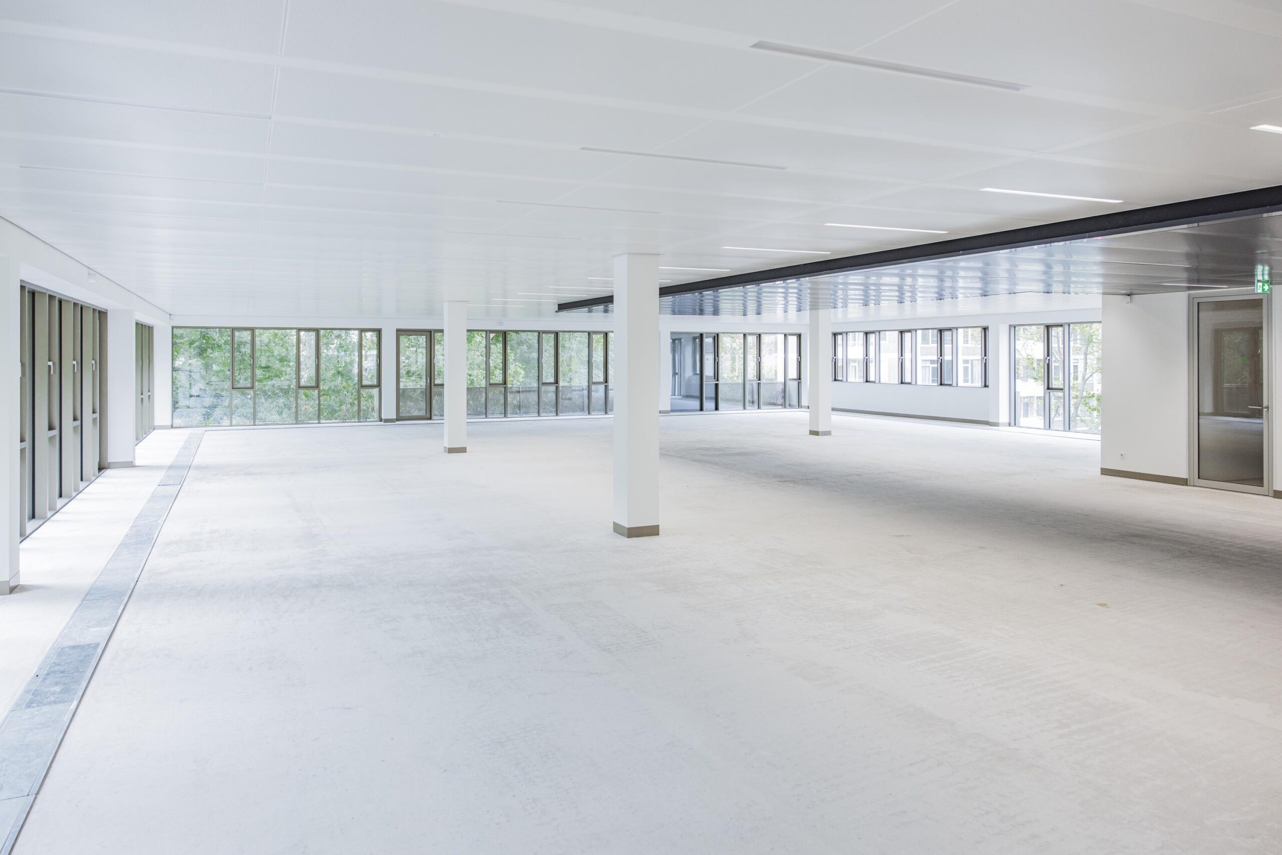 Bright, empty office space with large windows and white walls in the Walborg building.