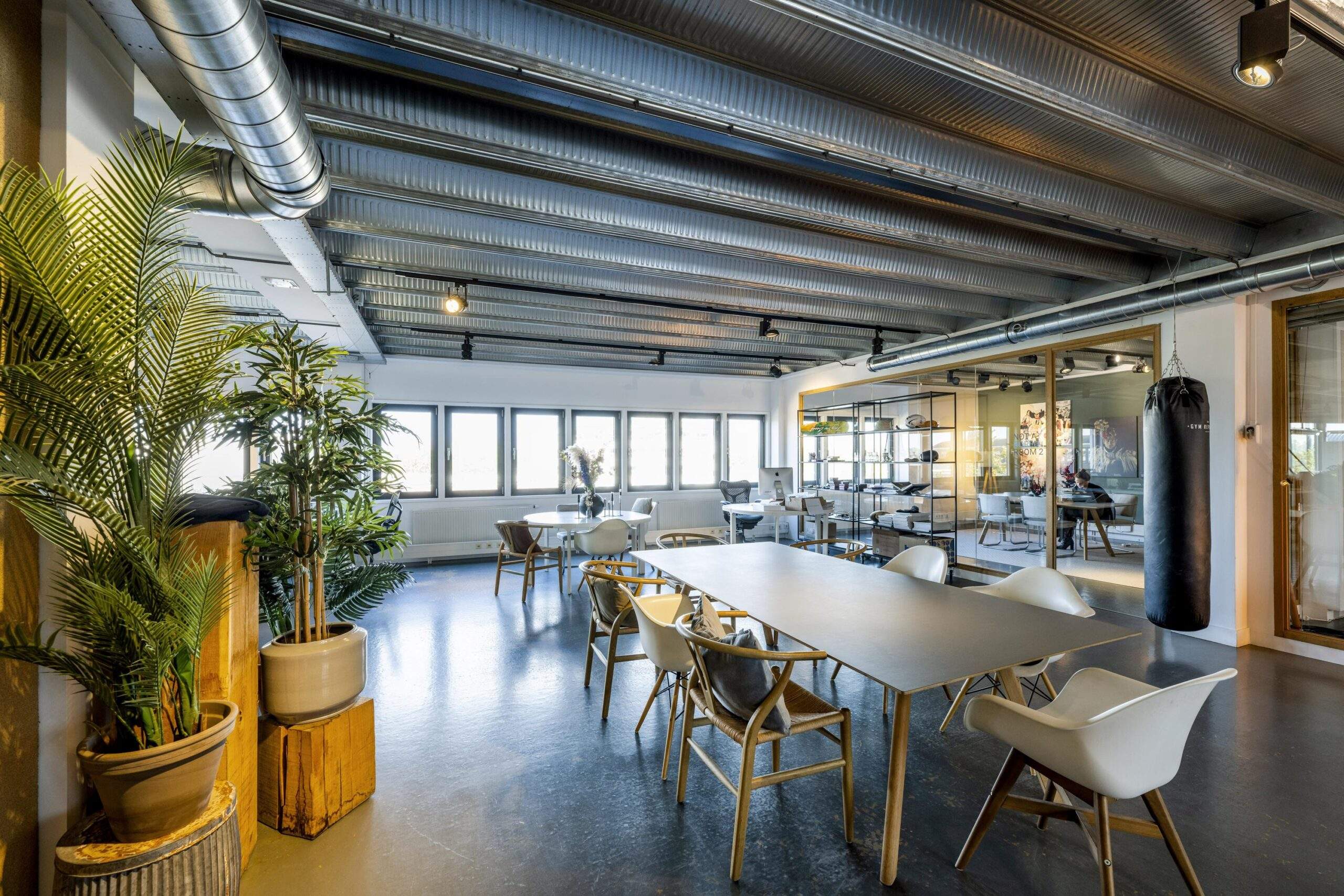 Modern industrial-style office space on Helicopterstraat with large windows, plants, and a punching bag.