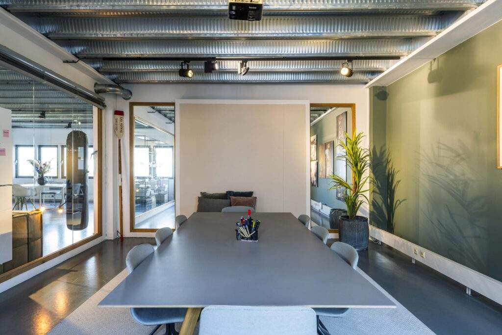 Modern meeting room on Helicopterstraat with a large conference table, grey chairs, and industrial ceiling design.