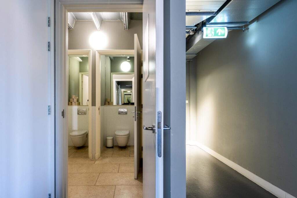 View through a door into a modern restroom area with mirrors creating an infinite reflection effect.