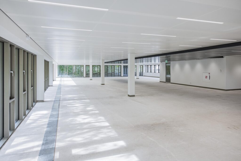 Lichte, lege kantoorruimte in het Walborg gebouw met grote ramen en witte plafonds.