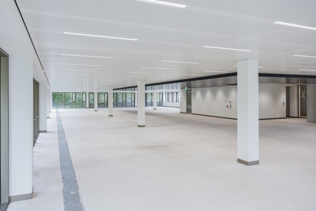 Lichte, lege kantoorruimte in het Walborg-gebouw met grote ramen en witte zuilen.