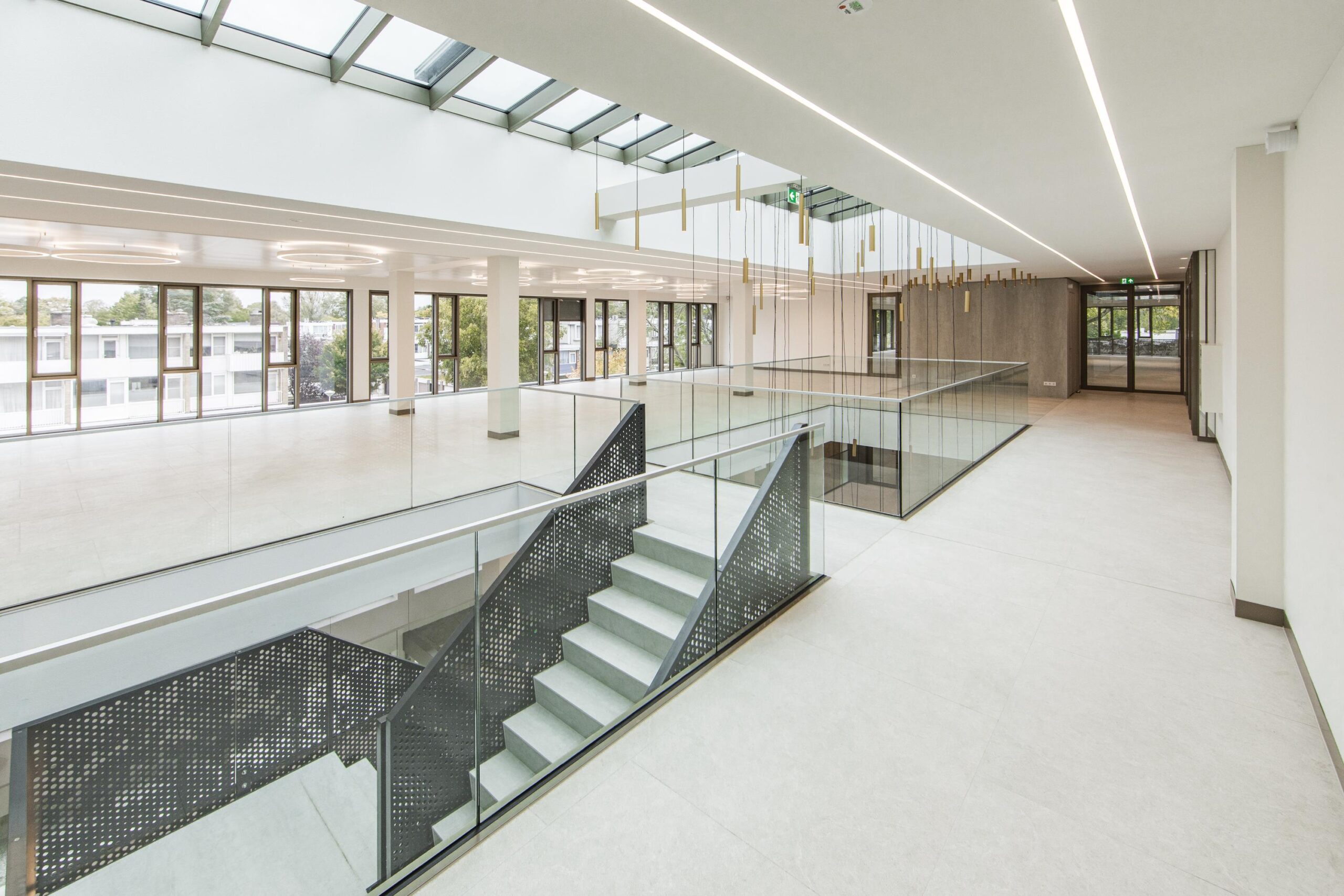Licht atrium met glazen balustrades, moderne trap en grote ramen in het Walborg-gebouw.