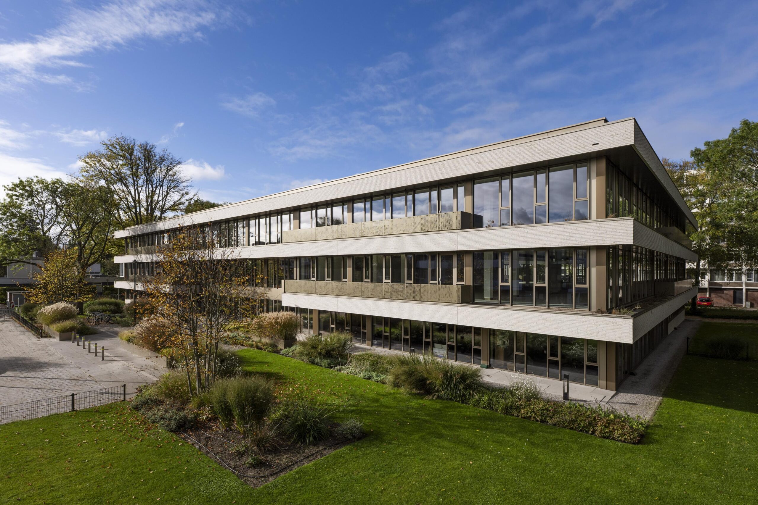 Modern kantoorgebouw Walborg met veel glas en groen rondom, onder een heldere blauwe lucht.