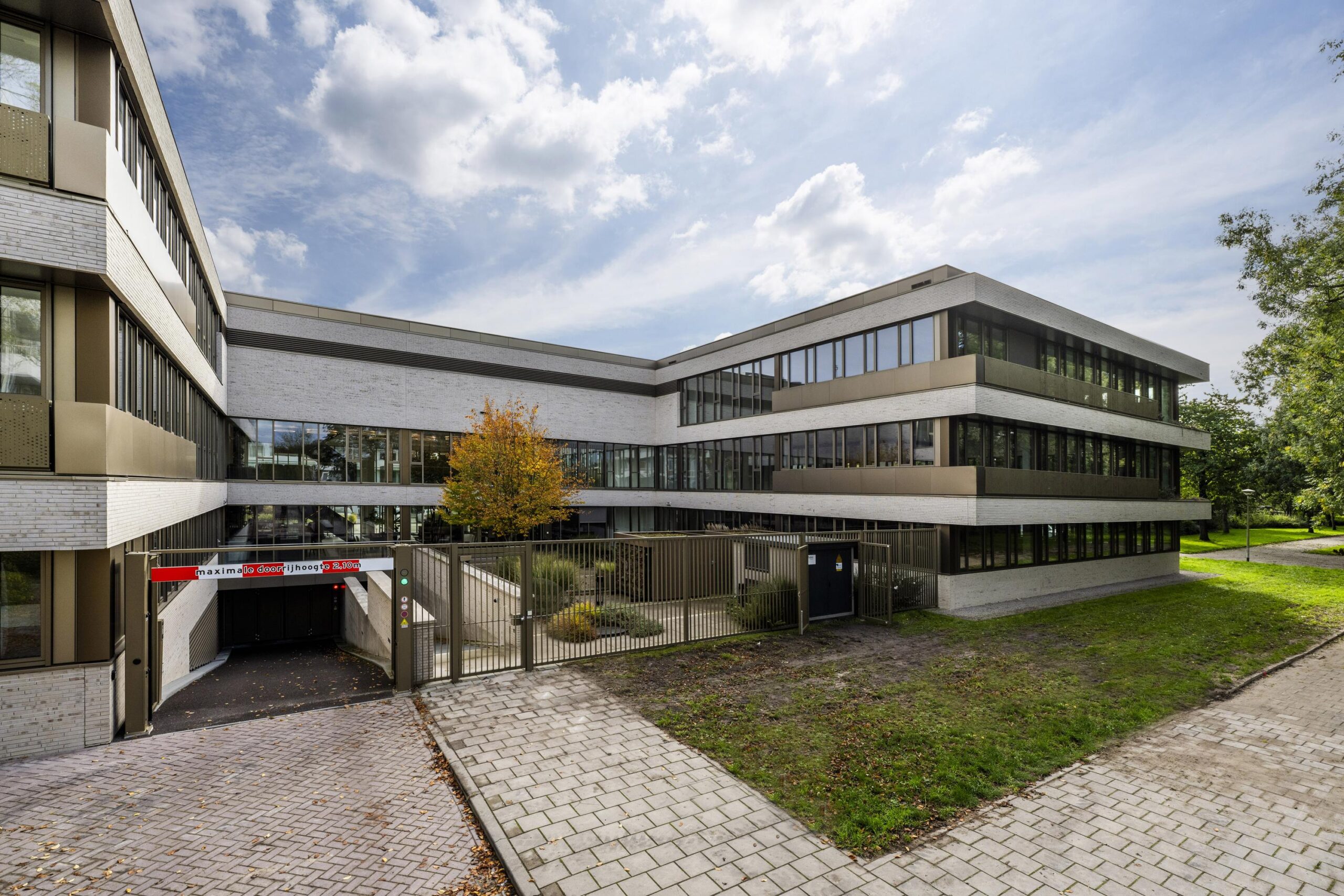 Modern kantoorgebouw Walborg met grote ramen, een ondergrondse parkeergarage en omliggend groen.