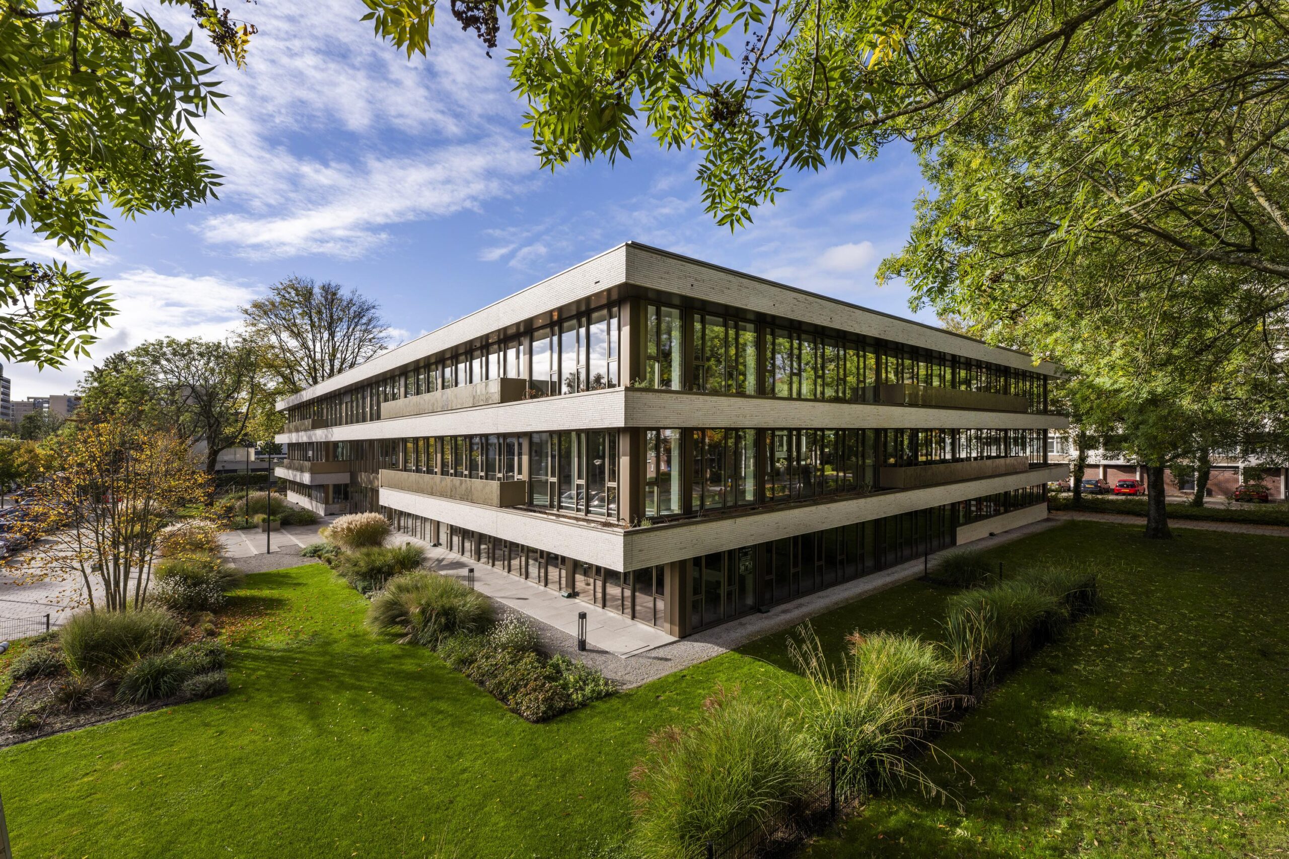 Modern kantoorgebouw Walborg omgeven door groen en bomen onder een blauwe lucht.