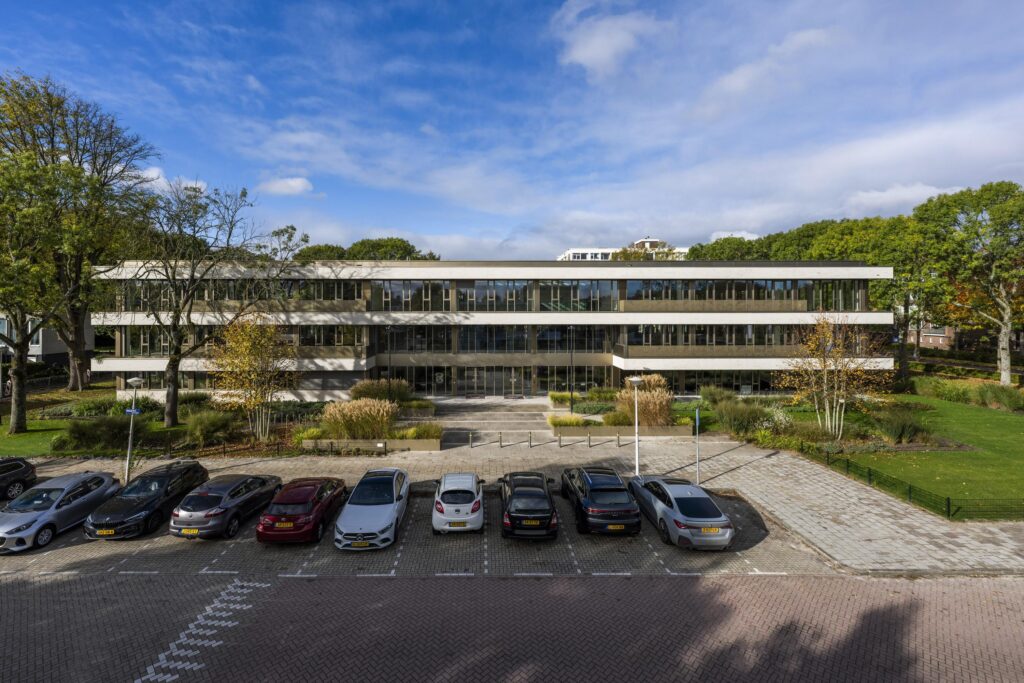 Modern kantoorgebouw Walborg met een parkeerterrein op de voorgrond en omringd door groen.