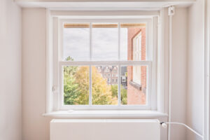 View through a white-framed window showing trees and traditional brick buildings in Address_7.