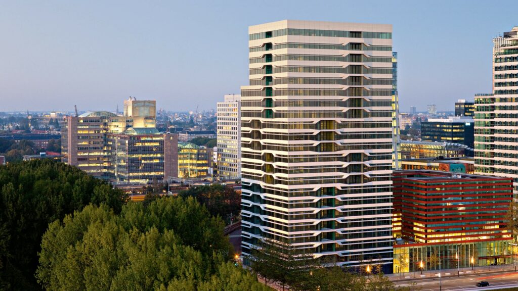 Modern kantoorgebouw aan de Parnassusweg in Amsterdam omgeven door andere hoogbouw en groen.
