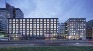Evening view of the illuminated Piet Hein Building with modern glass facades and a connected skybridge.