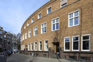 Curved brick residential building with white-framed windows on Concertgebouwplein in Amsterdam.