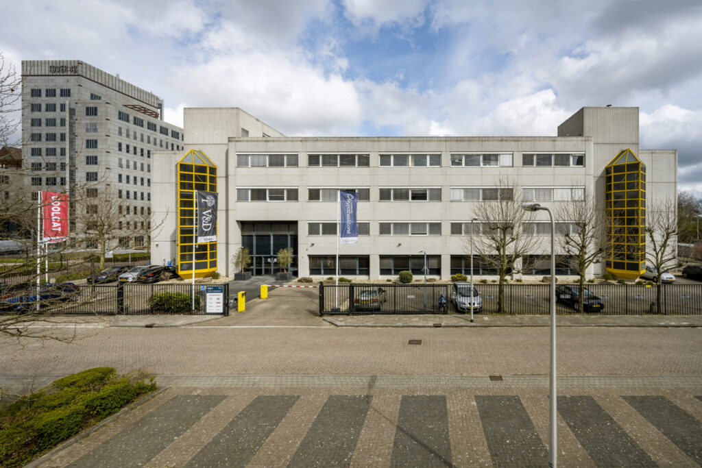 Voorgevel van kantoorgebouw Diemermere 003 met opvallende gele raamkozijnen en vlaggen van huurders aan de gevel.